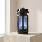 A black electric fly trap with a glowing blue insect-catching grid, sitting on a light beige stone pedestal in a softly lit indoor setting.