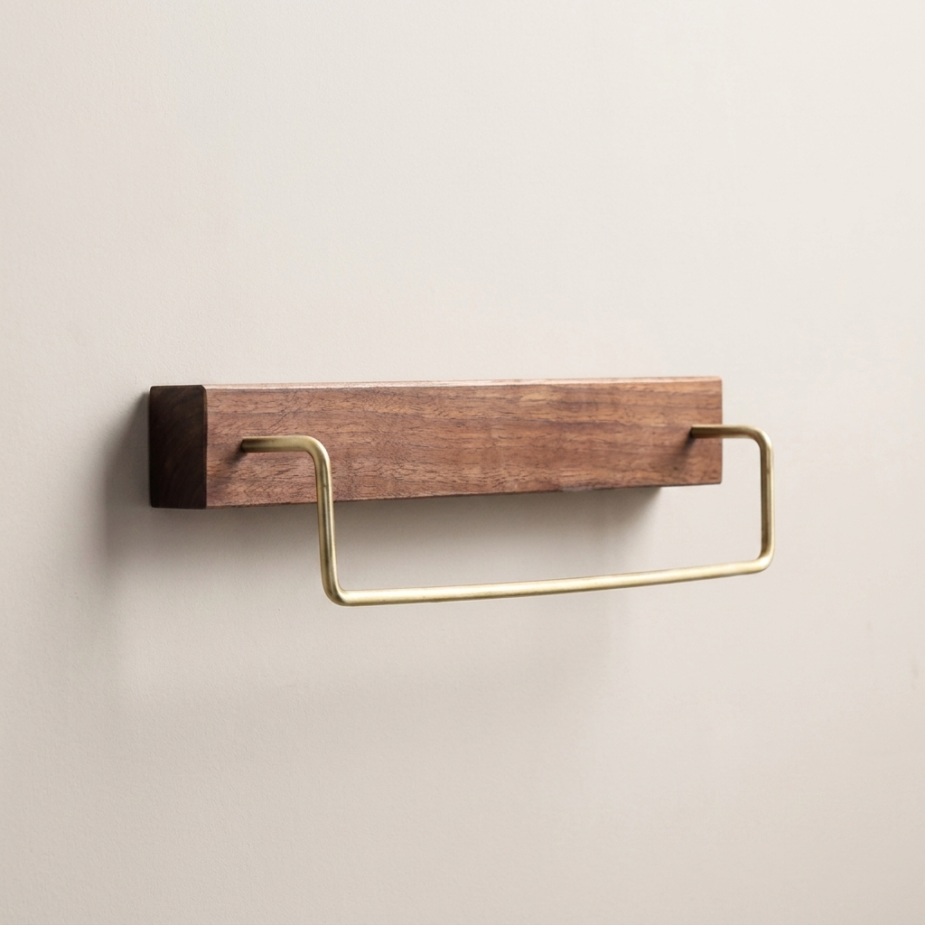 A wall-mounted bathroom towel bar with a rectangular wood backplate and a curved brass metal loop, shown against a plain light beige wall.