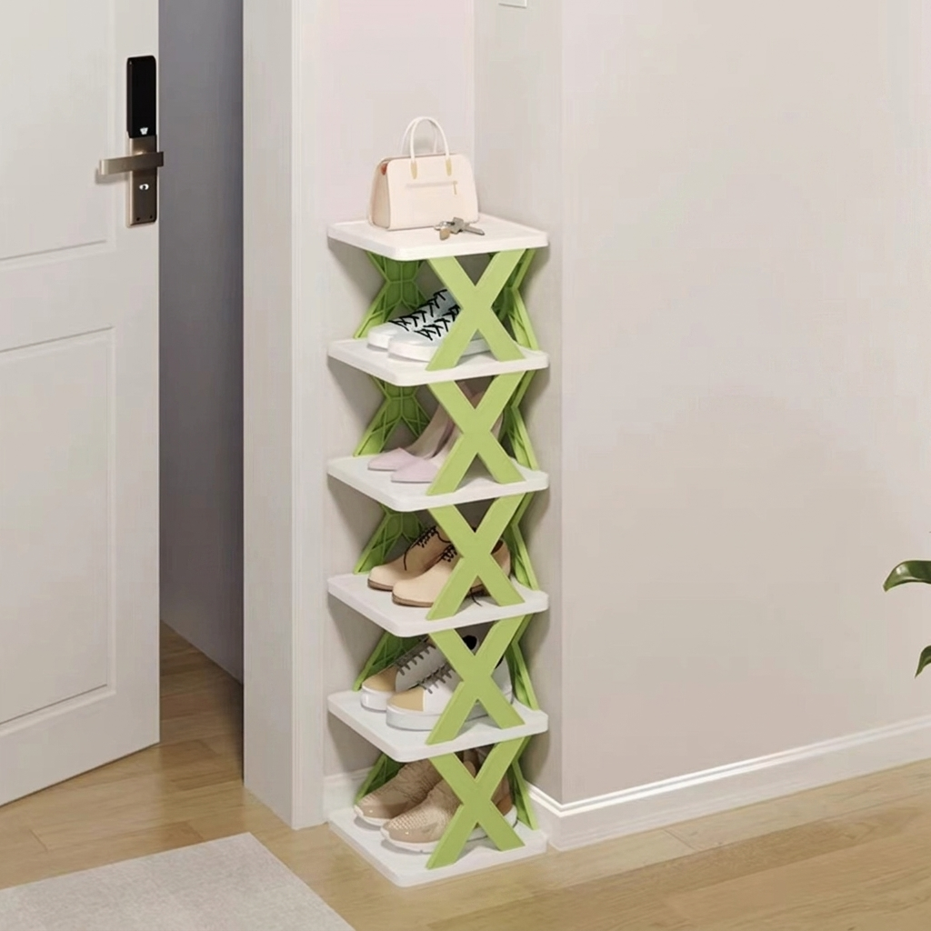 A slim white 5-tier shoe rack with green X-shaped side supports, shown in a home entryway next to a white door, holding several pairs of shoes and a handbag.