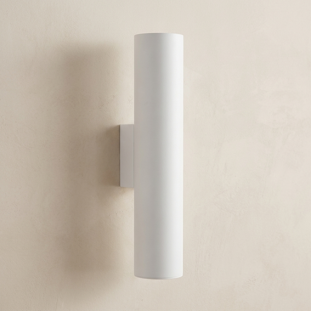 A minimalist white cylindrical wall sconce mounted on a textured beige plaster wall.