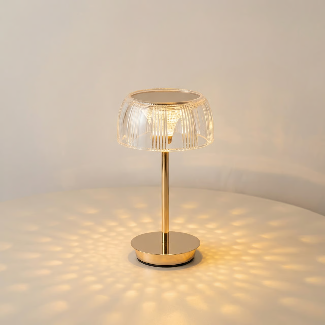 Gold table lamp with a clear glass shade on a light gray background
