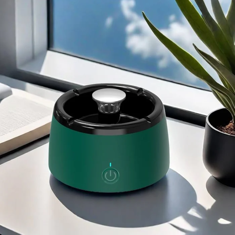 Green humidifier on a desk with a computer monitor and plant in the background