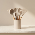 Set of kitchen utensils in a beige container on a light surface with a neutral background