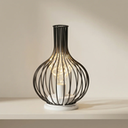 Decorative table lamp with black wire cage design on a neutral background