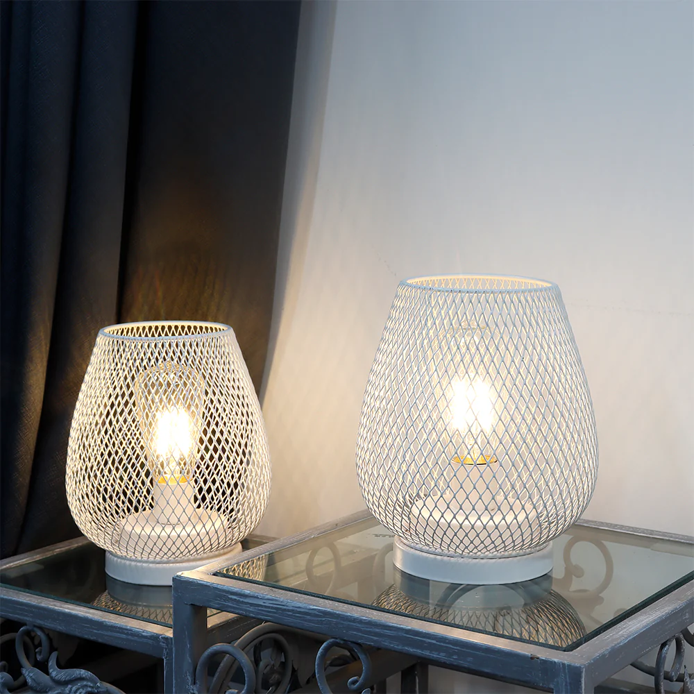 Two mesh-patterned table lamps on a glass table with a neutral background