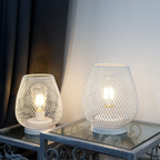 Two mesh-patterned table lamps on a glass table with a neutral background