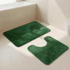 Green bath mat with leaf pattern on a bathroom floor.