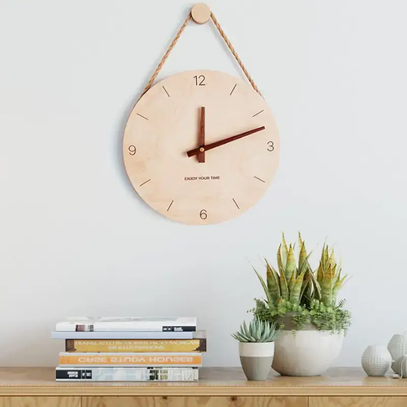 Wooden wall clock hanging on a light blue wall above a wooden shelf with books and plants.