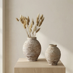 Two rustic ceramic vases on a wooden surface with a neutral background