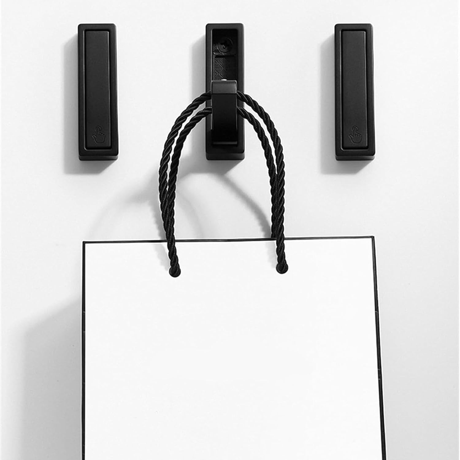 Black magnetic clip holding a piece of paper against a white background