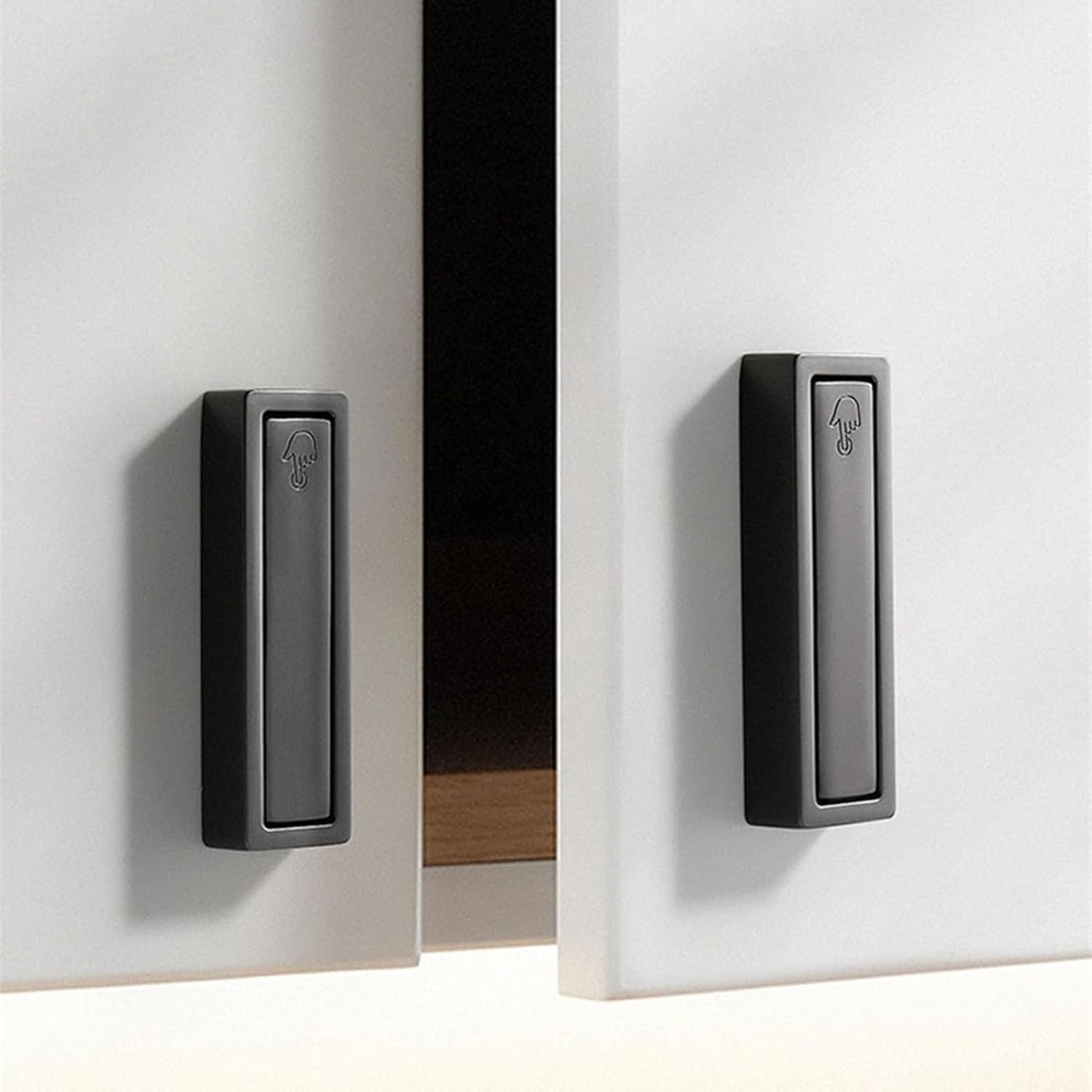 Two black rectangular doorbell buttons mounted on a white wall.