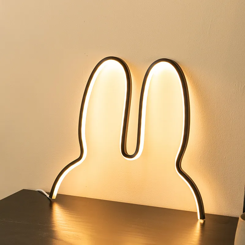 Modern LED lamp with U-shaped design on a wooden surface against a beige wall.