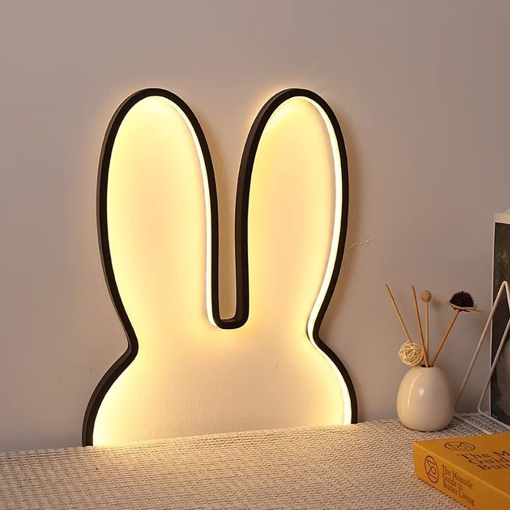 Bunny-shaped LED night light on a bed with a neutral background