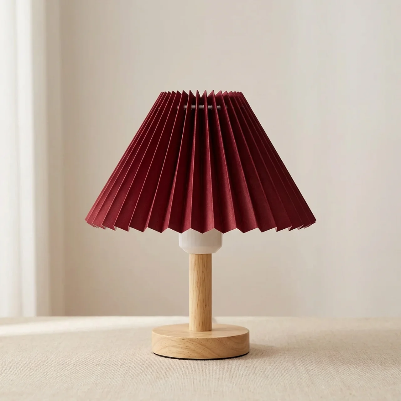Table lamp with a pleated red shade and wooden base on a neutral background