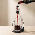 Red wine being poured from a bottle into a decanter on a neutral background