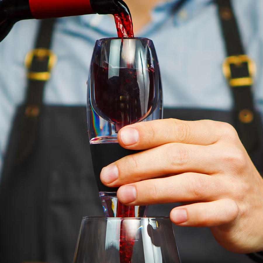 Person pouring red wine into a glass with a blurred background