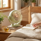Light green fan on a wooden nightstand next to a person reading a book in a bedroom.