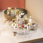 Round glass tray with skincare and makeup products on a marble surface.