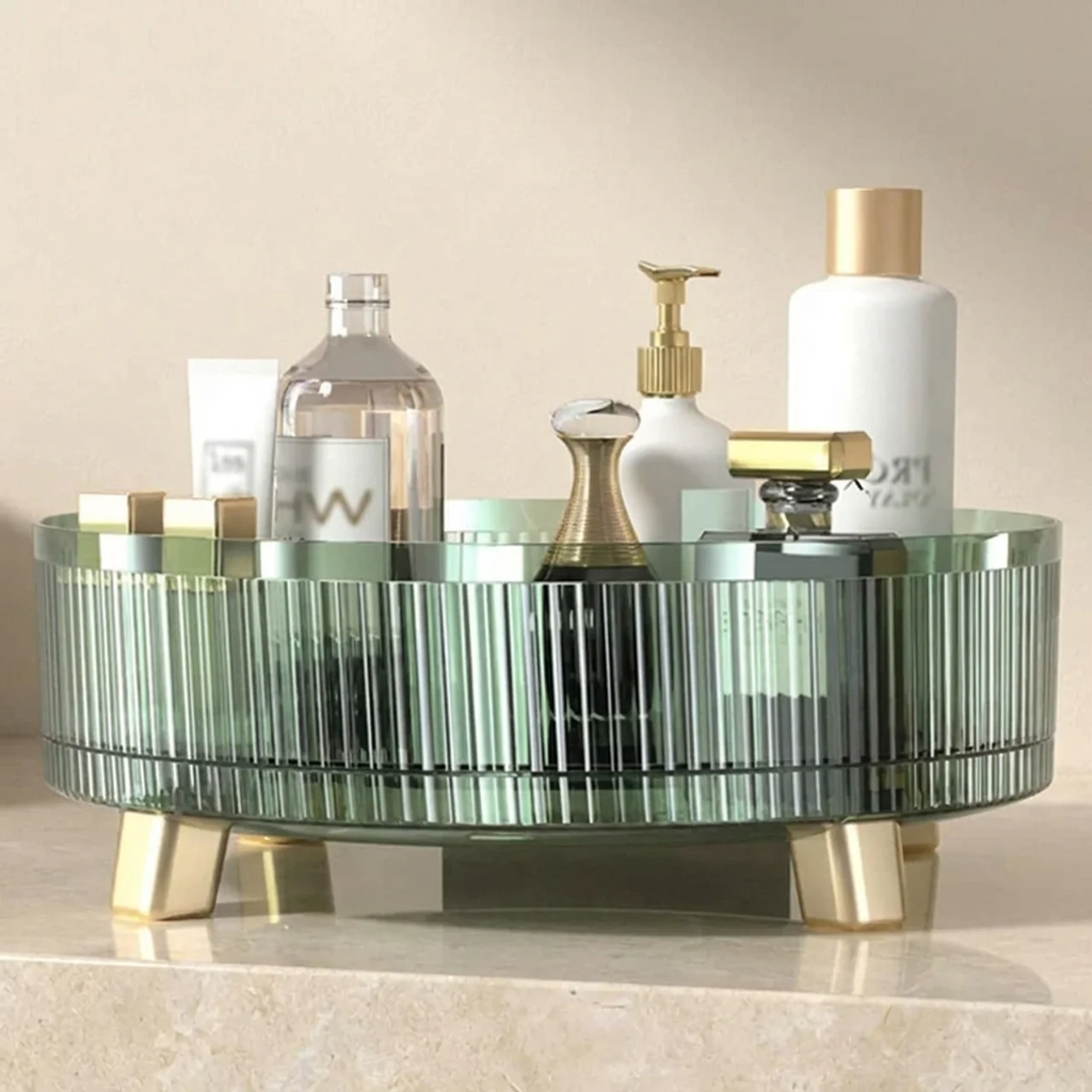 Round glass tray with gold legs holding various bottles on a beige surface.