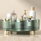 Round glass tray with gold legs holding various bottles on a beige surface.