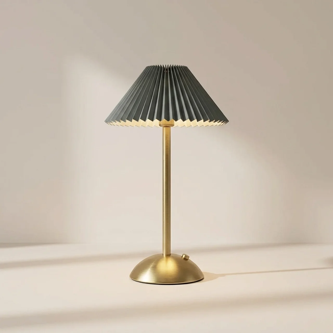 Table lamp with pleated gray shade and gold base on a neutral background