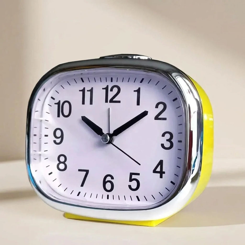 Yellow alarm clock with a white face on a beige background