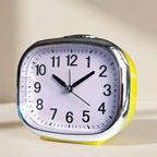 Yellow alarm clock with a white face on a beige background