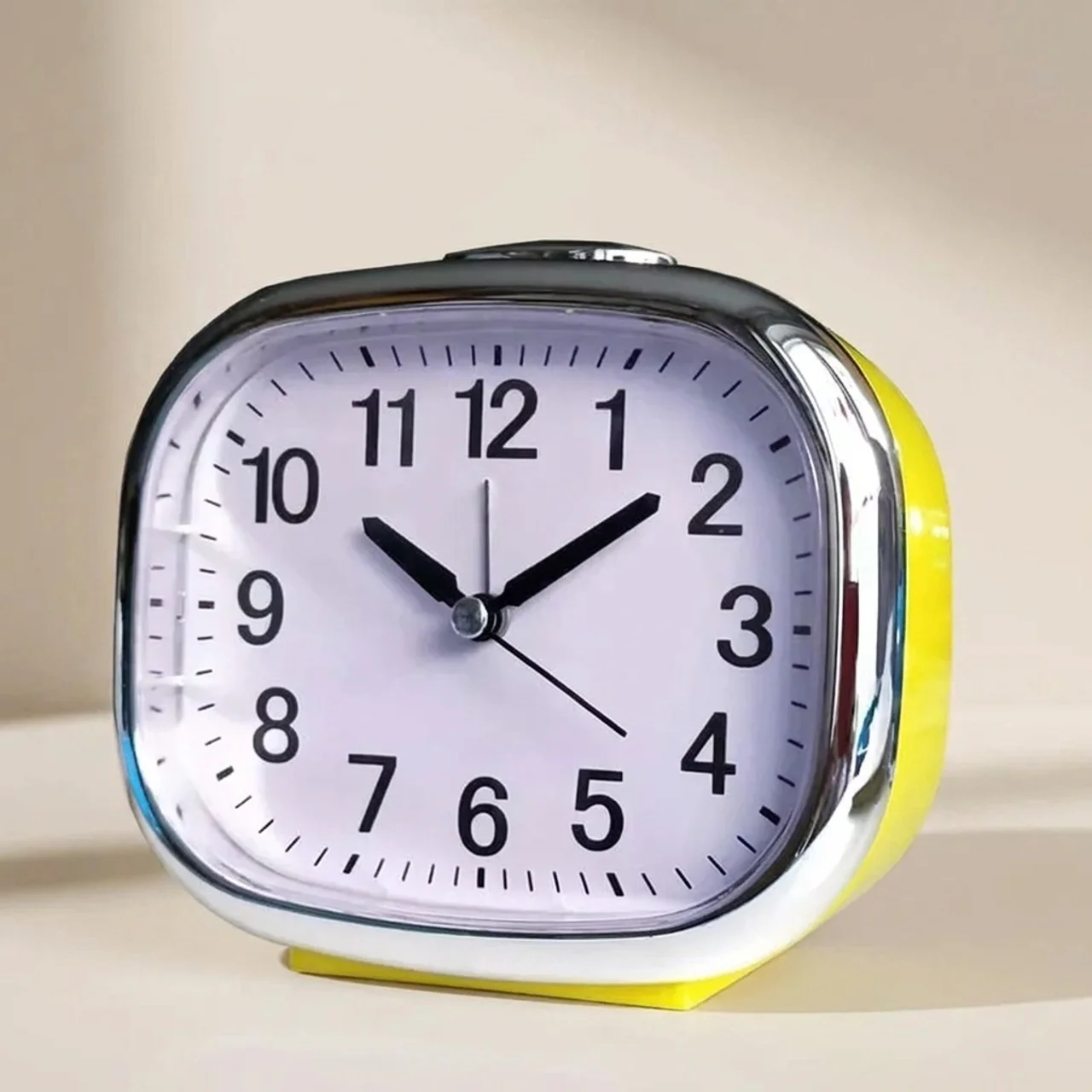 Yellow alarm clock with a white face on a beige background
