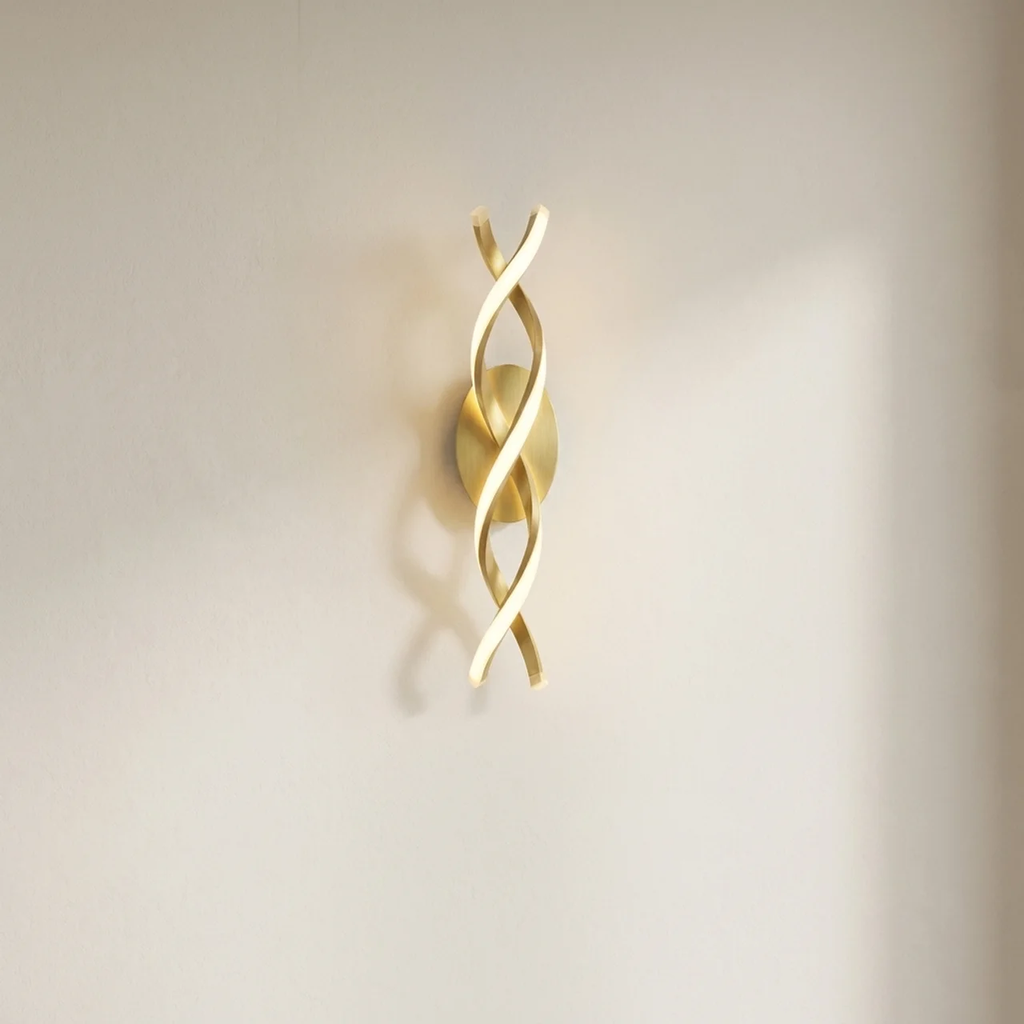Gold wall sconce with wavy design on a neutral background