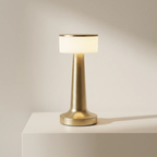 Gold table lamp with white shade on a beige background