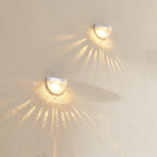 Two wall-mounted lights casting shadows on a textured wall.