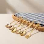 Set of gold cutlery on a wooden tray with a checkered cloth in the background