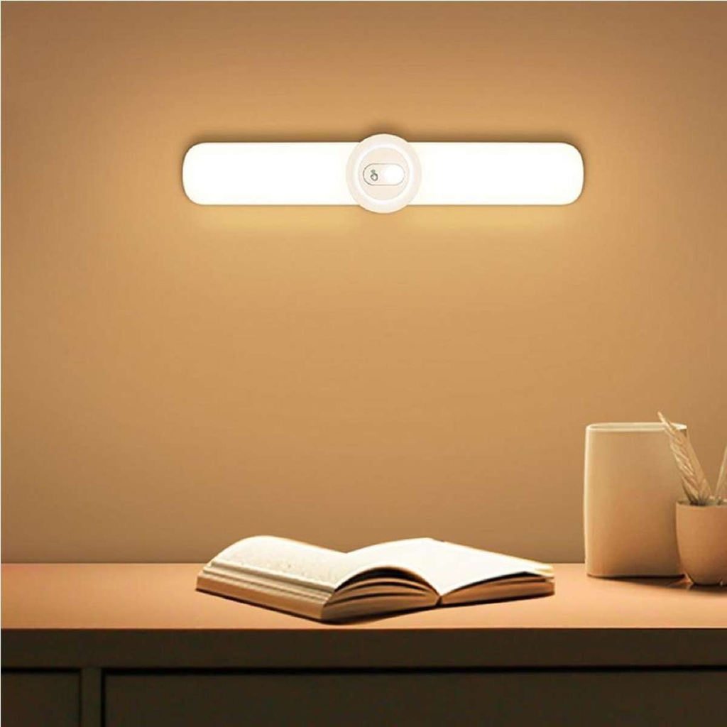 Wall-mounted light fixture on a wall with a table and book in the foreground