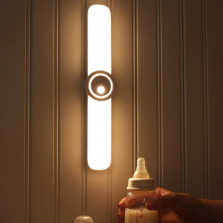 Bottle being held in front of a wall-mounted light fixture