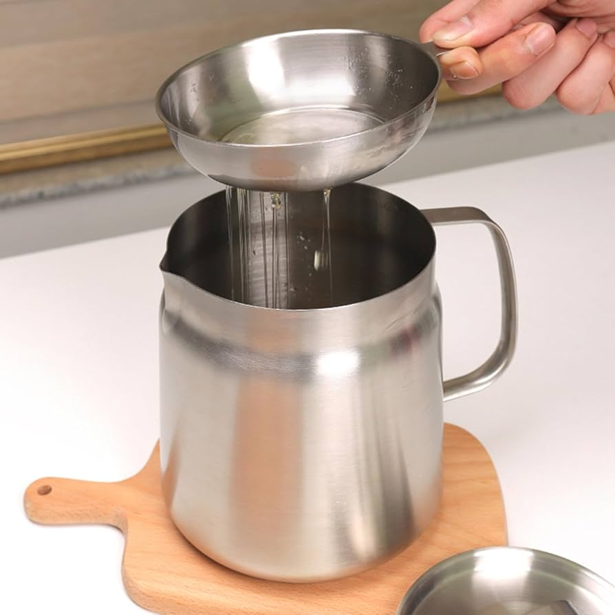 Stainless steel strainer being used over a metal pitcher on a wooden cutting board.