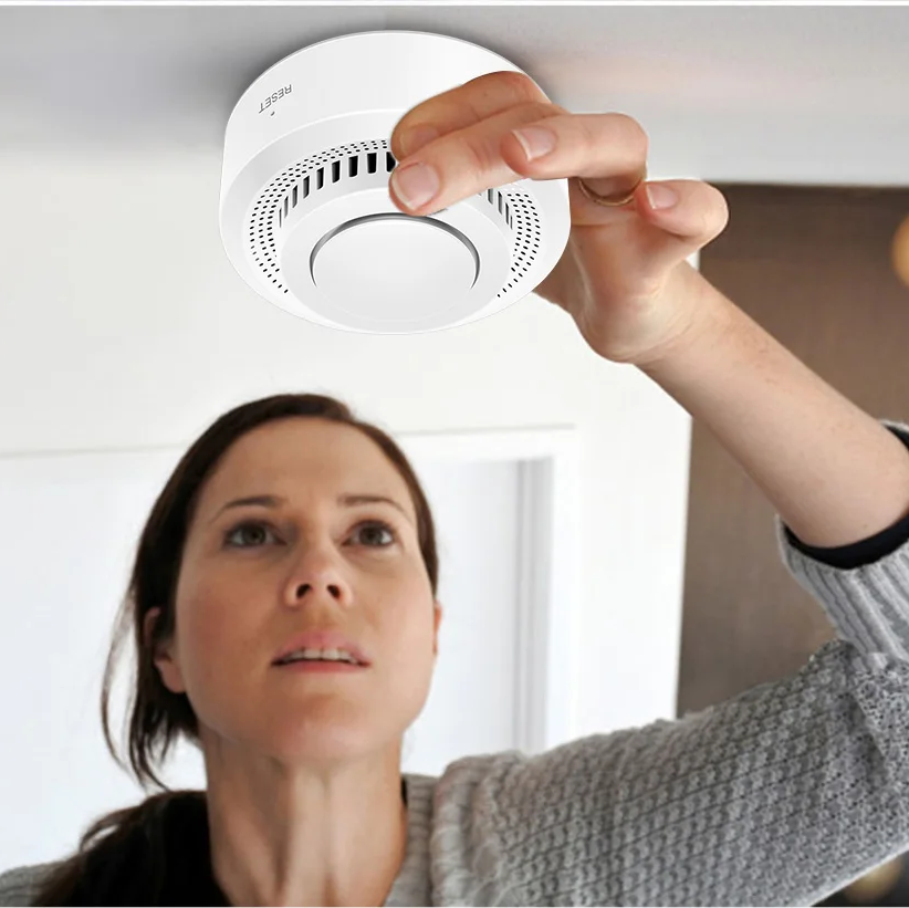 Woman installing a smoke detector on a ceiling