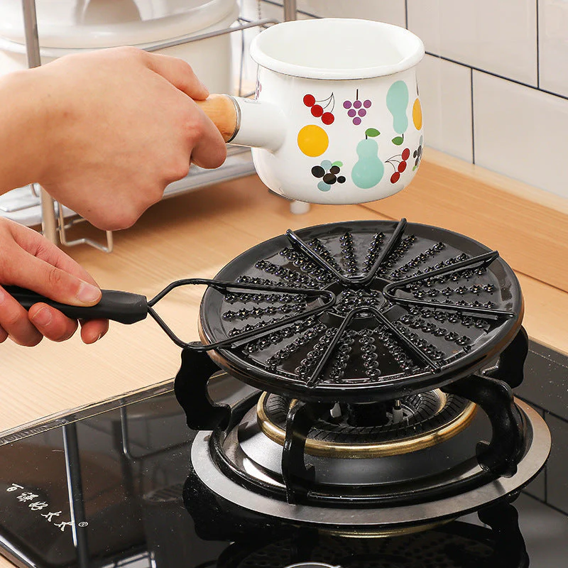 Person using a black waffle maker on a stove with a colorful mug in the background.