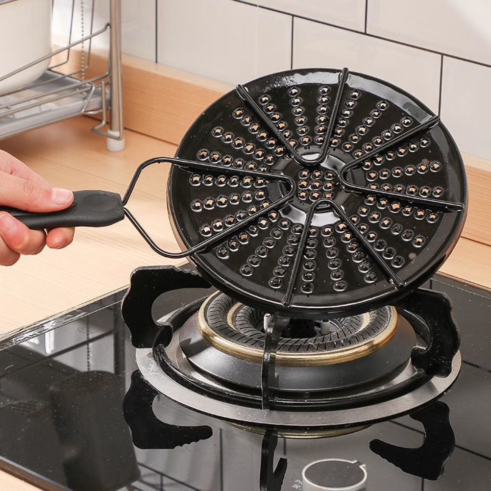 Black waffle maker on a stove with a hand holding a tool