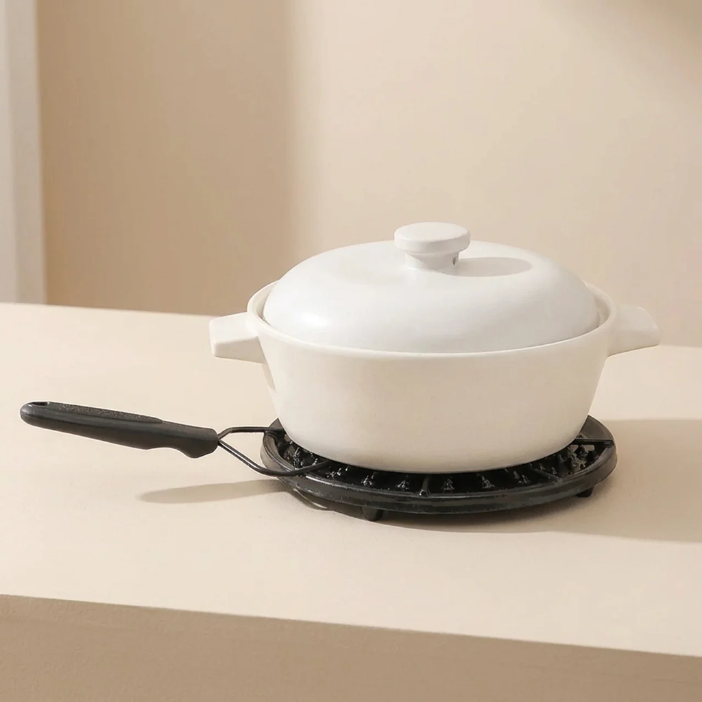 White ceramic pot with a black handle on a beige surface