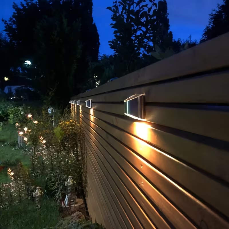 Wooden fence with embedded lights in a garden setting at night