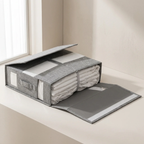 Gray fabric storage box with a mattress inside on a light wooden floor.