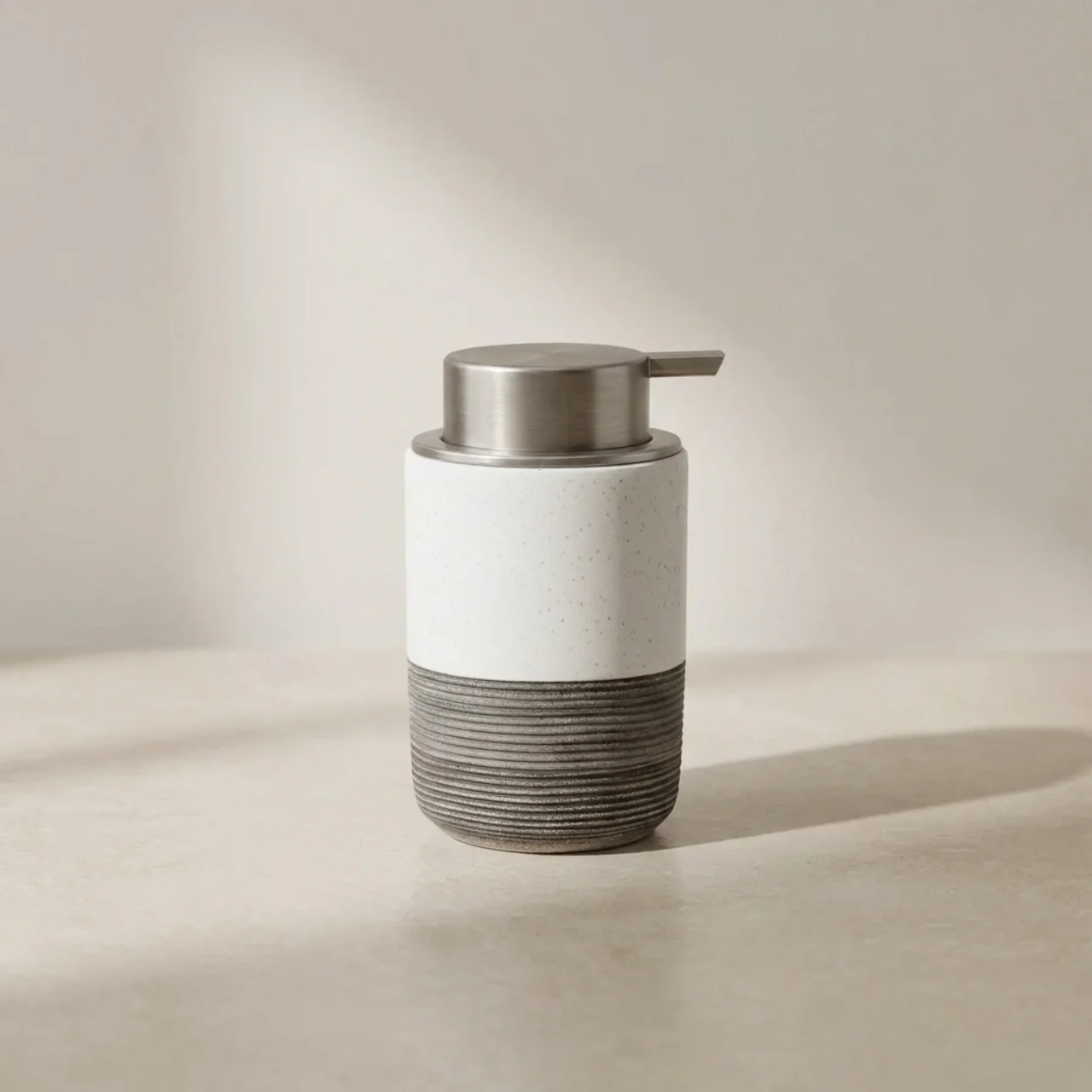 Soap dispenser with a white body and gray base on a beige background