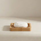 White bar of soap in a wooden soap dish on a beige background