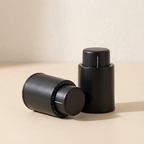 Two black cylindrical objects on a beige surface with a neutral background