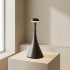 Modern black lamp on a light-colored pedestal against a neutral wall.