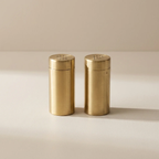 Two gold-colored salt and pepper shakers on a beige background