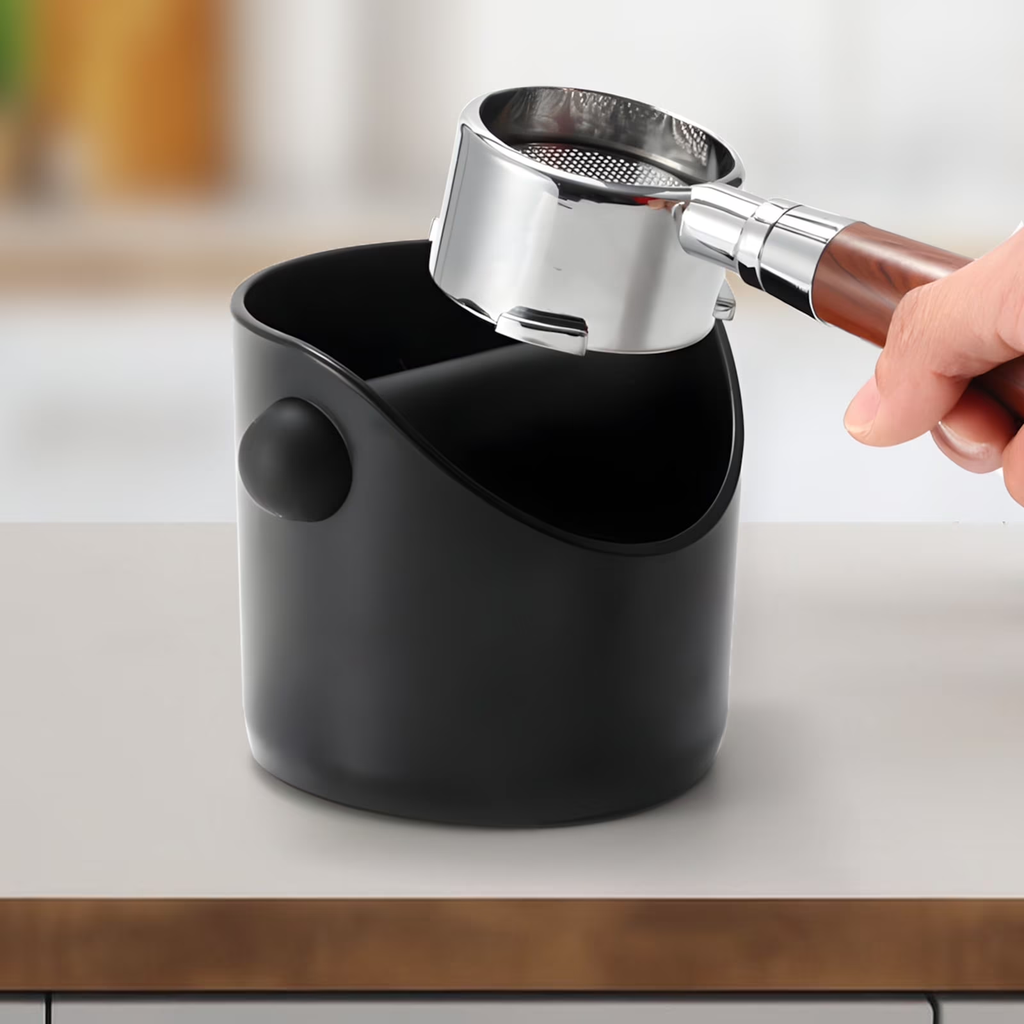 Black container with a hand holding a metal scoop over it on a kitchen counter.