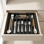 Open kitchen drawer with organized cutlery and utensils on a black tray.