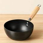 Black wok with a wooden handle on a wooden surface