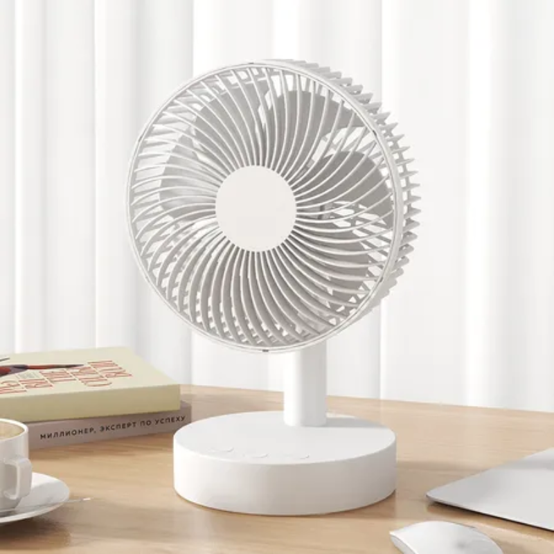 White desk fan on a wooden surface with a white curtain background